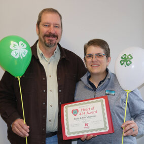 Tom & Becky Schuerman holding balloons and certificate.