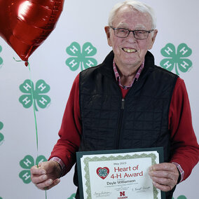 Man holding heart-shaped balloon and certificate which says Heart of 4-H Award