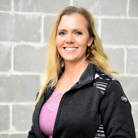 A smiling woman standing in front of a wall