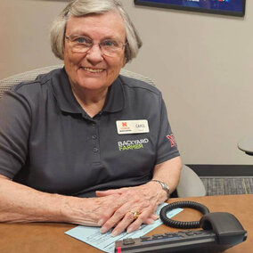 Smiling woman sitting at a desk with a phone in front of her