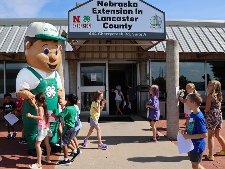 Front entrance of Lancaster County Extension building with a Lil' Green mascot greeting many youth