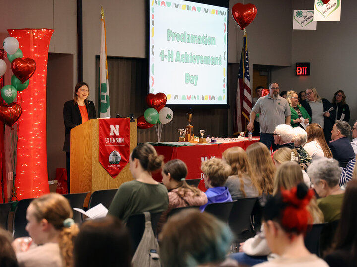 A woman speaking at a podium to a room full of seated people