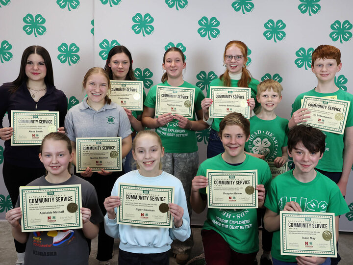 A group of two rows of youth holding certificates that say Community Service
