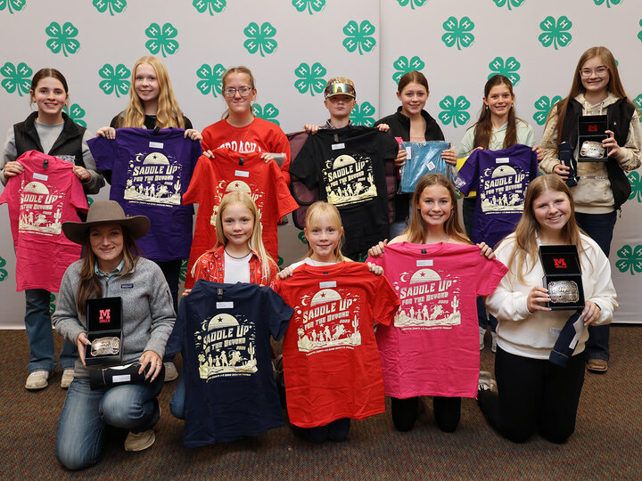 Two rows of youth holding shirts, belt buckles and other swag.