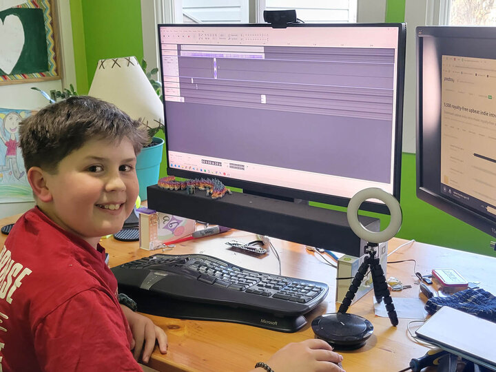 Boy sitting at computer which shows audio editing software