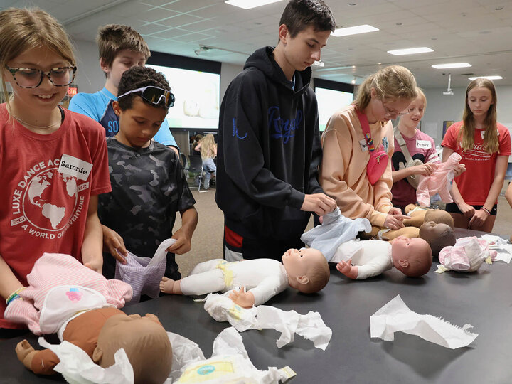 several youth practicing changing diapers on baby dolls