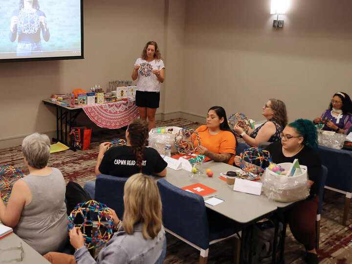 an educator leading several adults sitting at tables in a mindful breathing activity