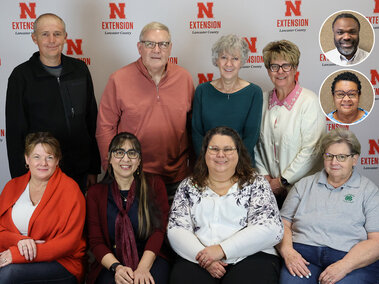 A group of two rows of adults with two headshots inset into the photo