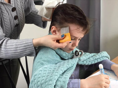 adult woman combing a boy's wet hair using a nit comb