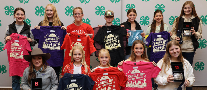 Two rows of youth holding T-shirts, belt buckles or other items