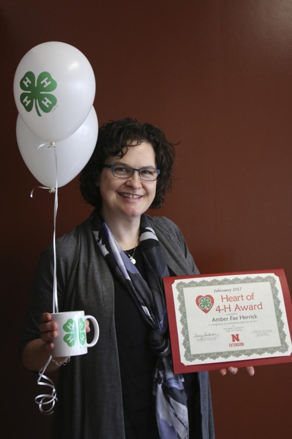 Amber Herrick holding 4-H ballons, a 4-H mug, and a certificate. 