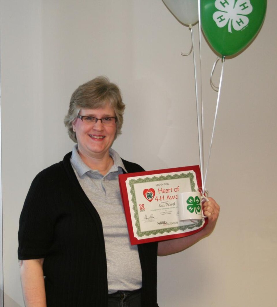 Ann Pickrel holding 4-H balloons and a certificate. 