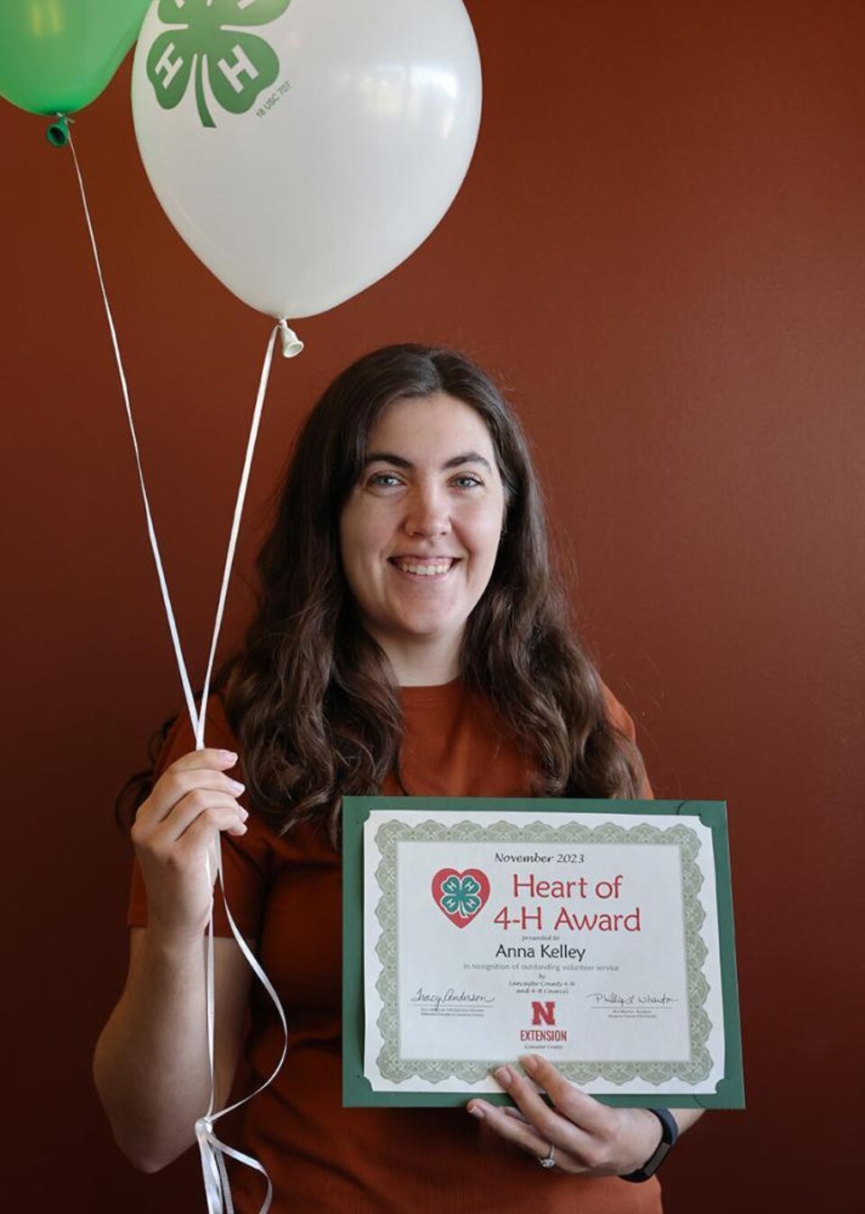 Anna Kelley holding certificate and balloons. 