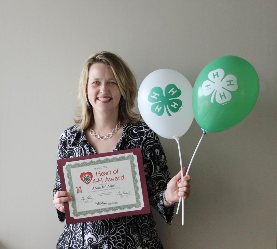 Anne Johnson holding 4-H balloons and a certificate. 