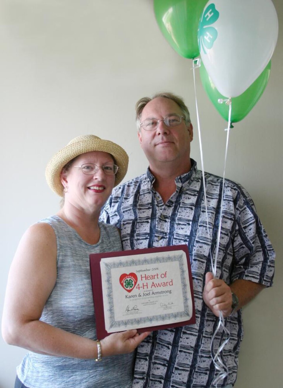 Karen and Joel Armstrong standing together and holding balloons and a certificate 