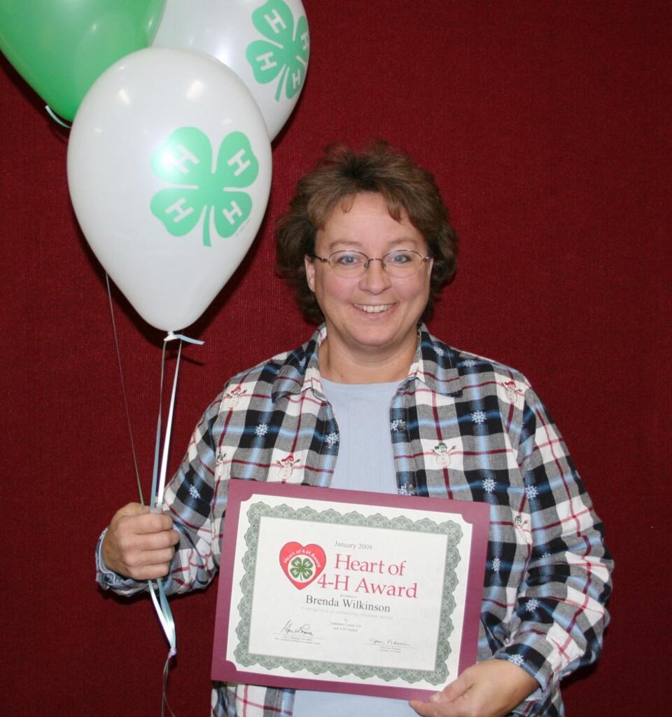 Brenda Wilkinson holding balloons and a certificate 