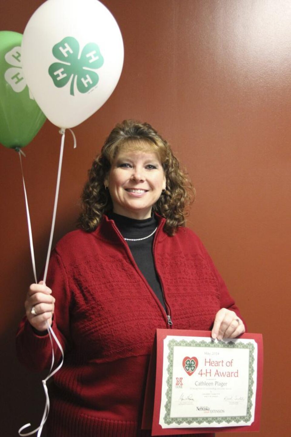 Cathy Plager holding 4-H balloons and a certificate. 