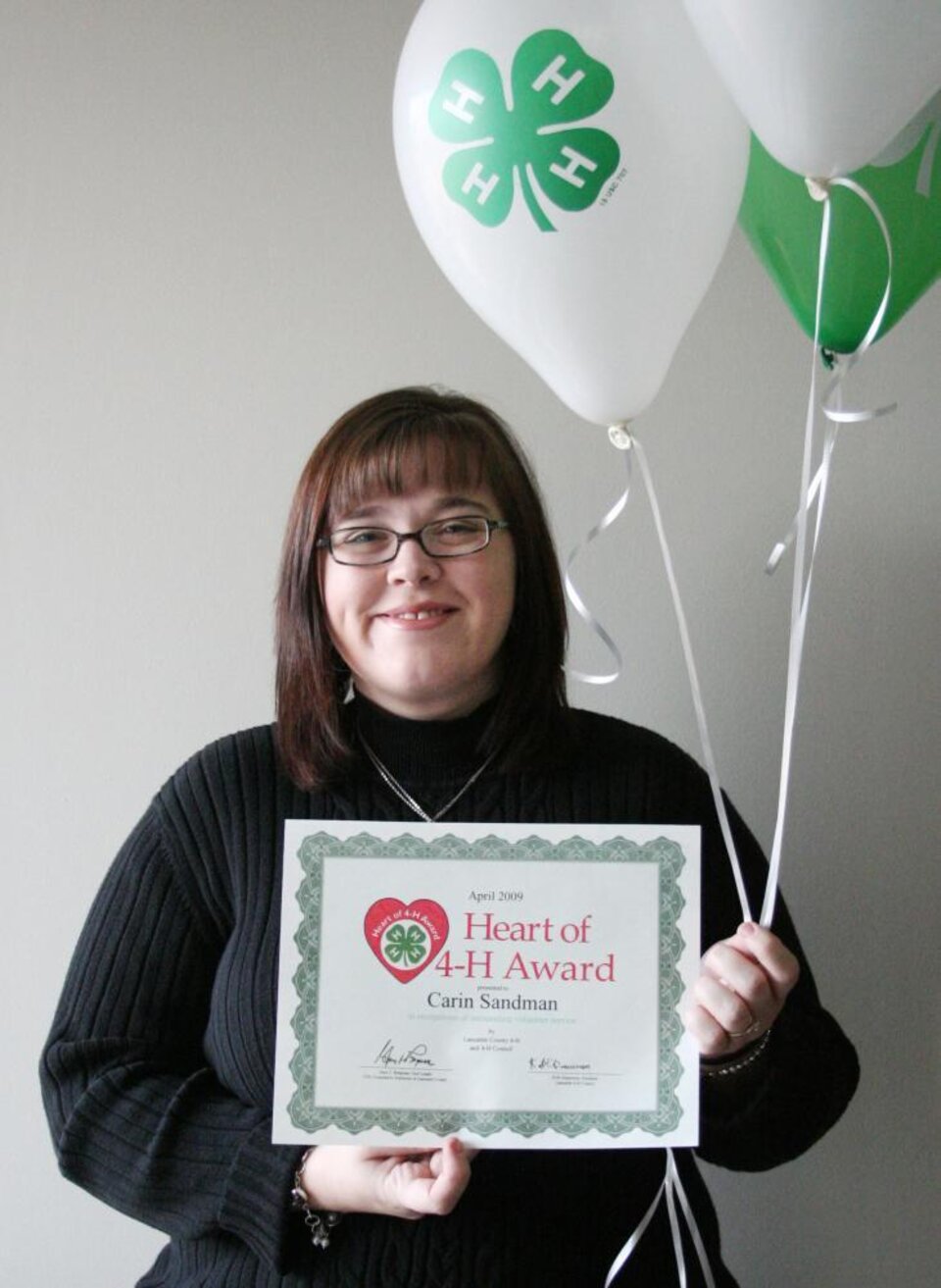 Carin Sandman holding balloons and a certificate 