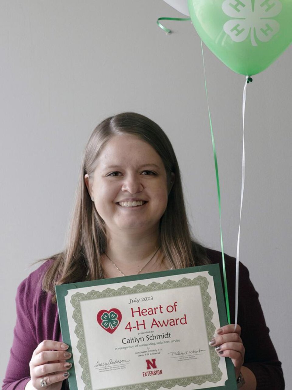 Caitlyn Schmidt holding certificate and balloons. 