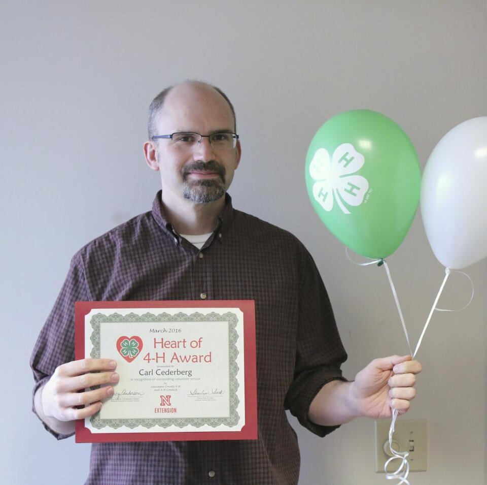 Carl Cederberg holding 4-H balloons and a certificate. 