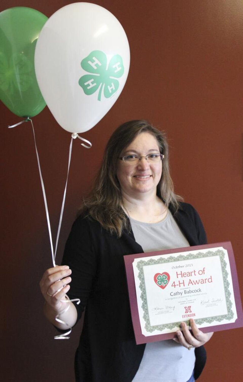 Cathy Babcock holding 4-H balloons and a certificate. 