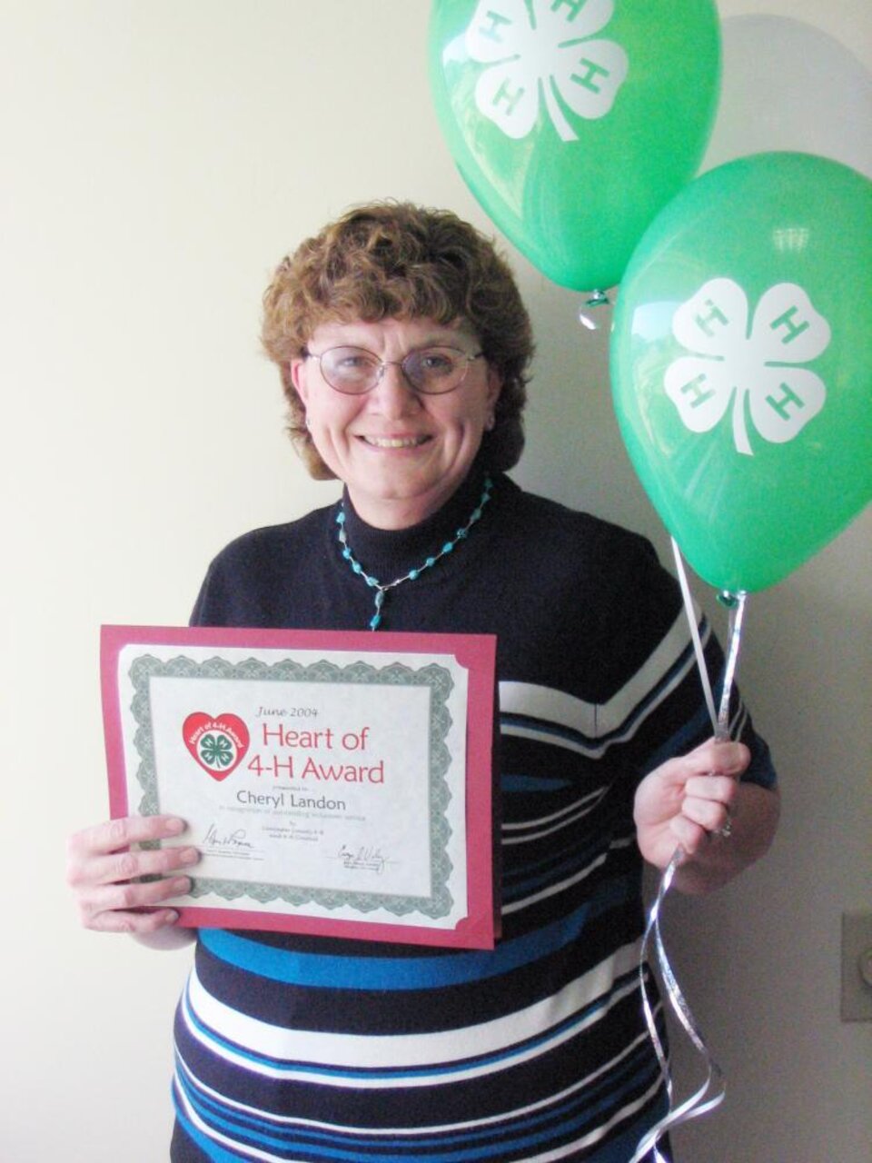 Cheryl Landon holding balloons and a certificate 