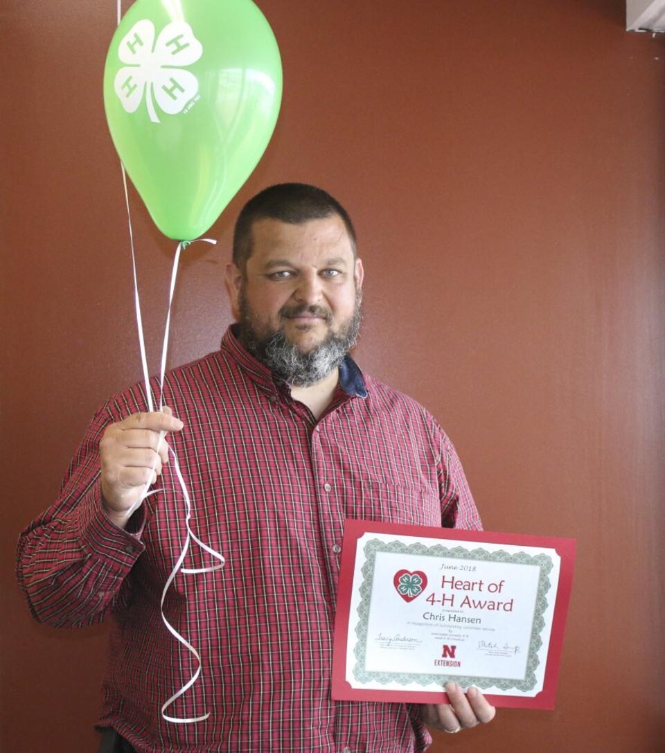 Chris Hansen holding 4-H balloons and a certificate. 