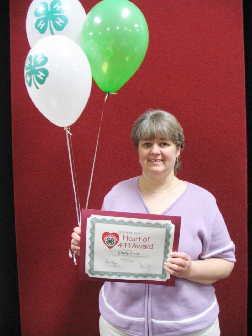 Cindy Faila holding balloons and a certificate 