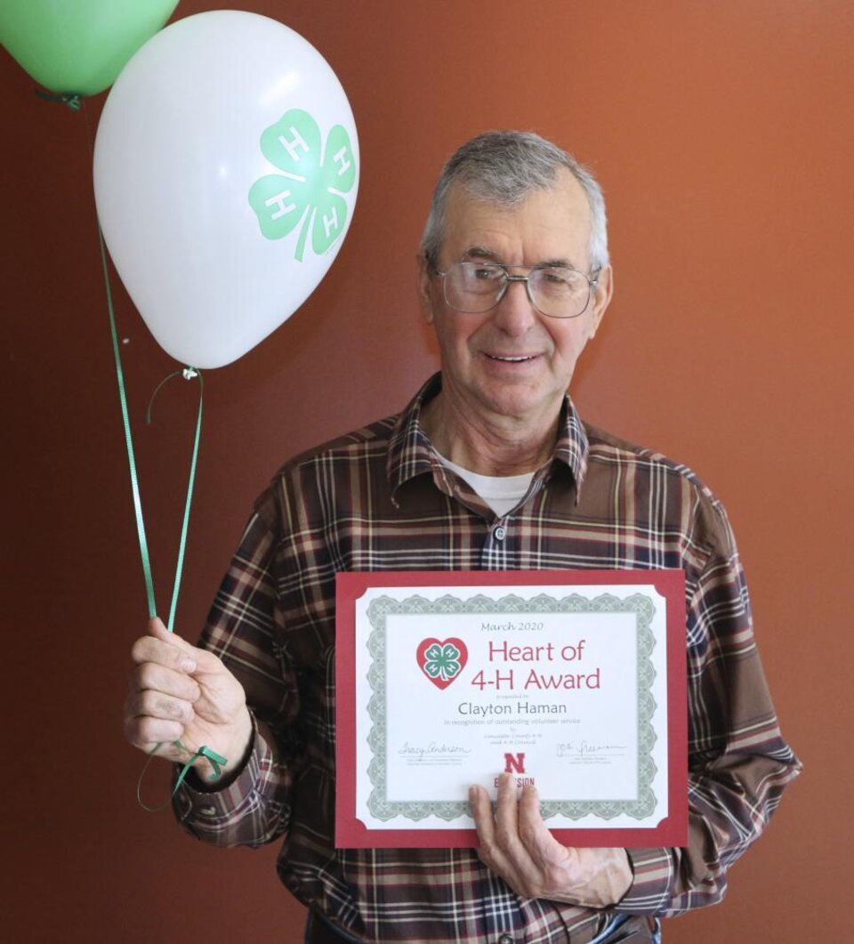 Clayton Haman holding 4-H balloons and a certificate. 