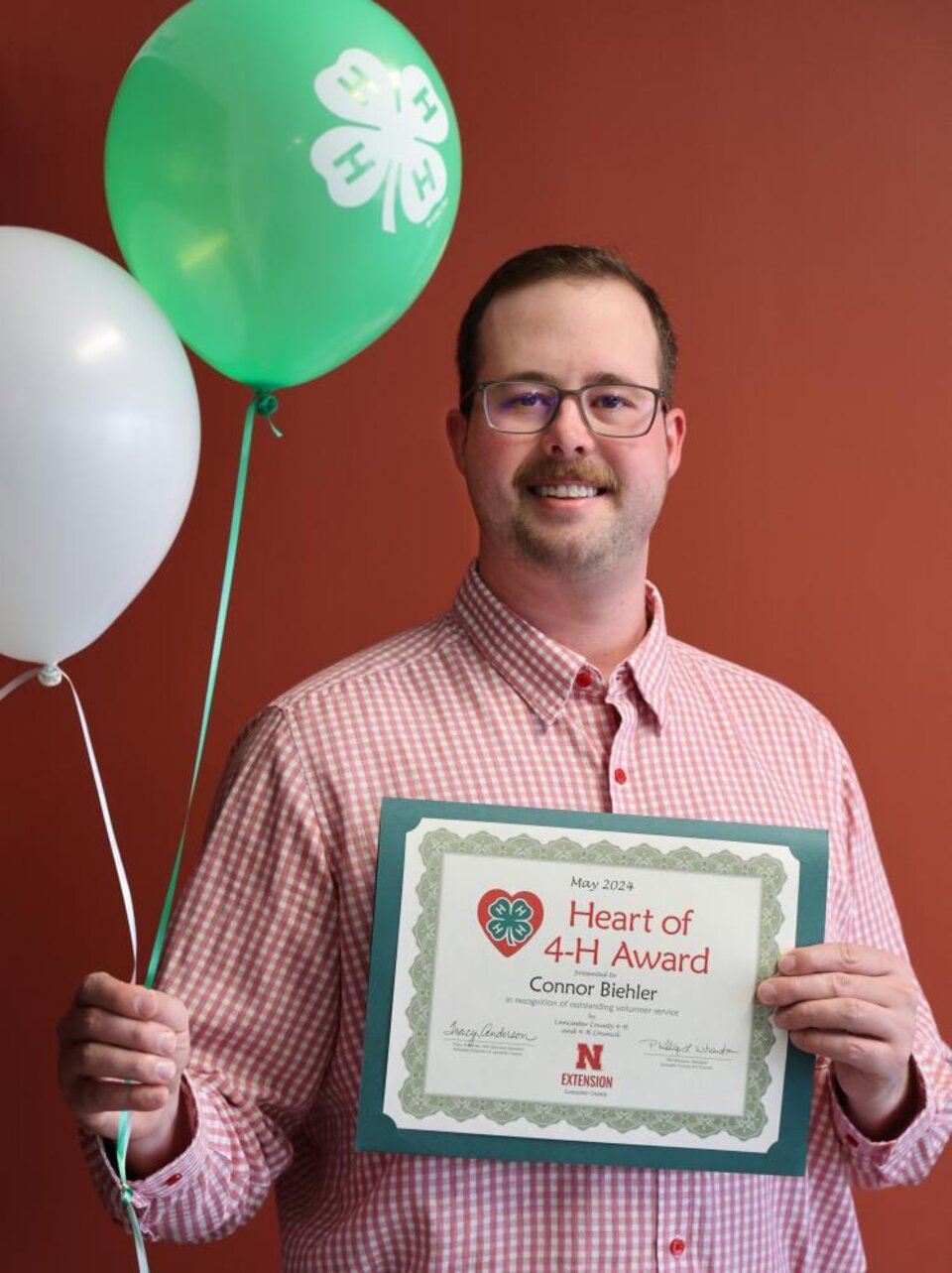 Connor Biehler holding certificate and balloons. 