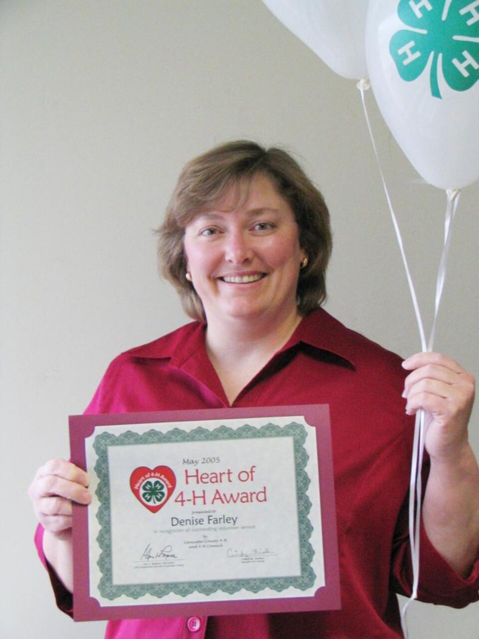 Denise Farley holding balloons and a certificate 