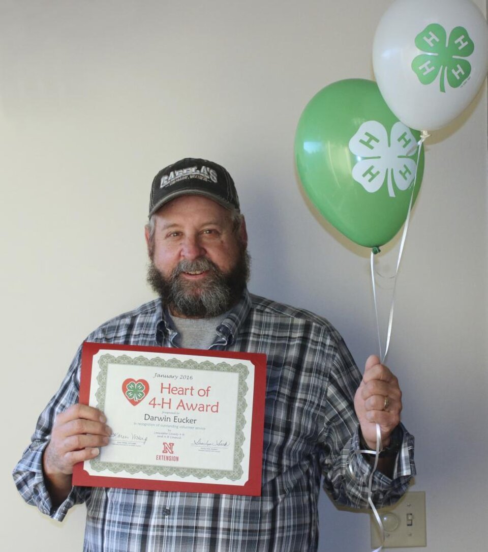 Darwin Eucker holding 4-H balloons and a certificate. 