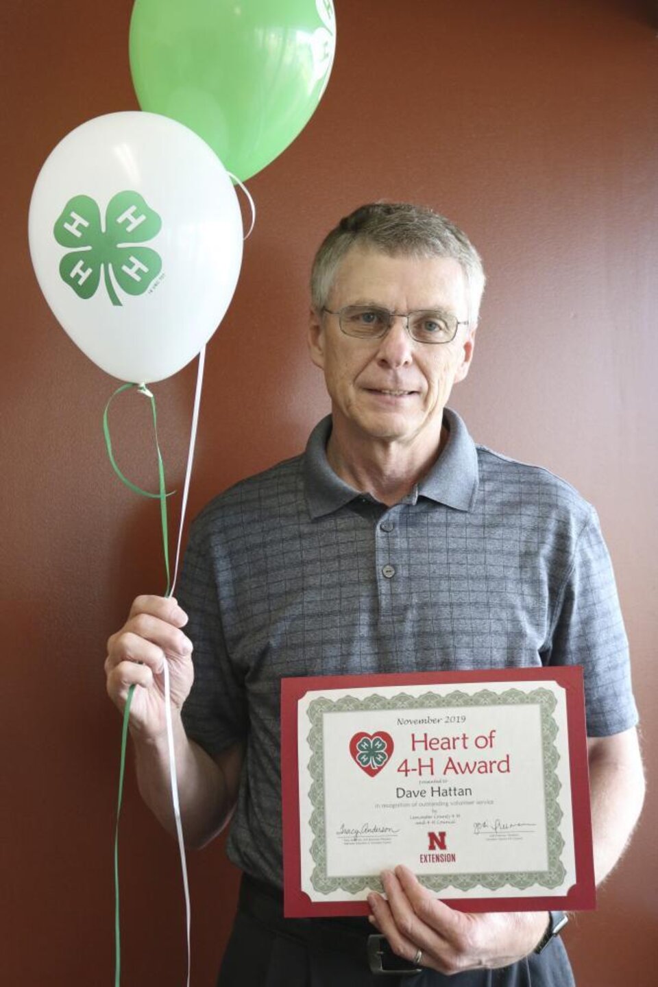 Dave Hattan holding 4-H balloons and a certificate. 