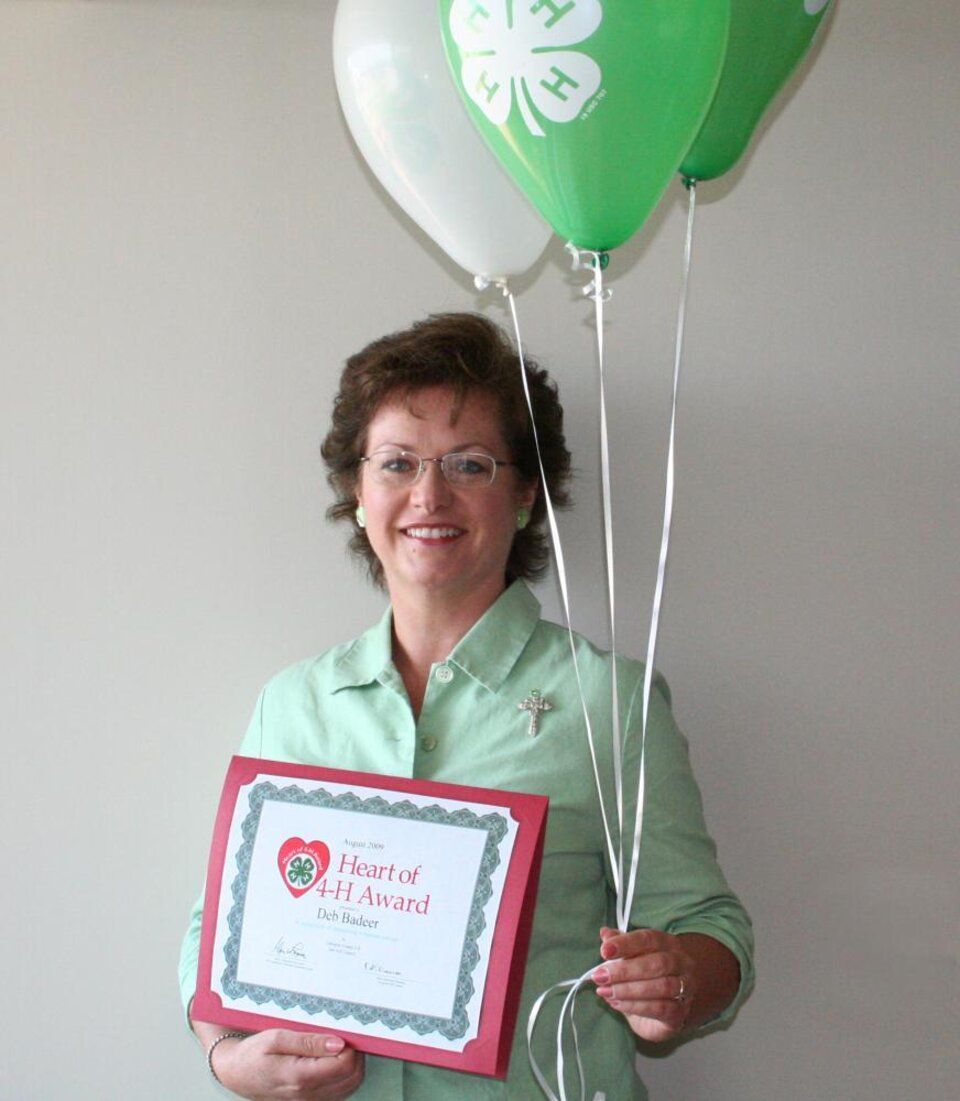 Deb Badeer holding balloons and a certificate 