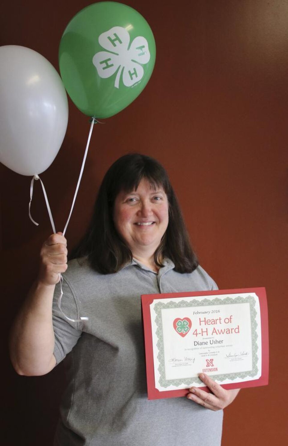 Diane Usher holding 4-H balloons and a certificate. 