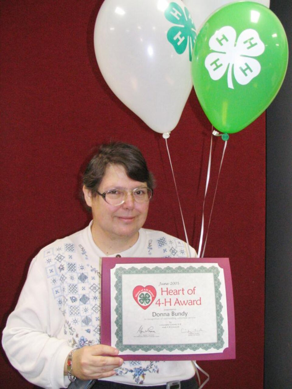 Donna Bundy holding balloons and a certificate 