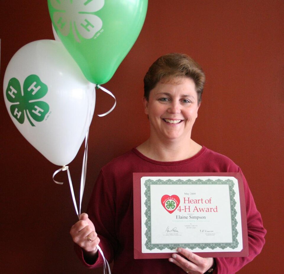 Elaine Simpson holding balloons and a certificate 