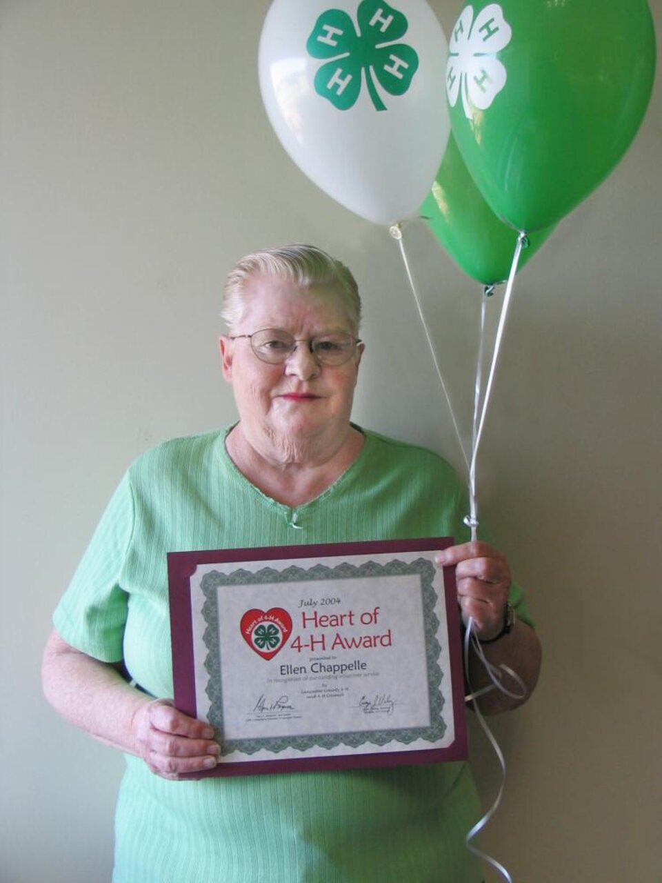 Ellen Chapelle holding balloons and a certificate 