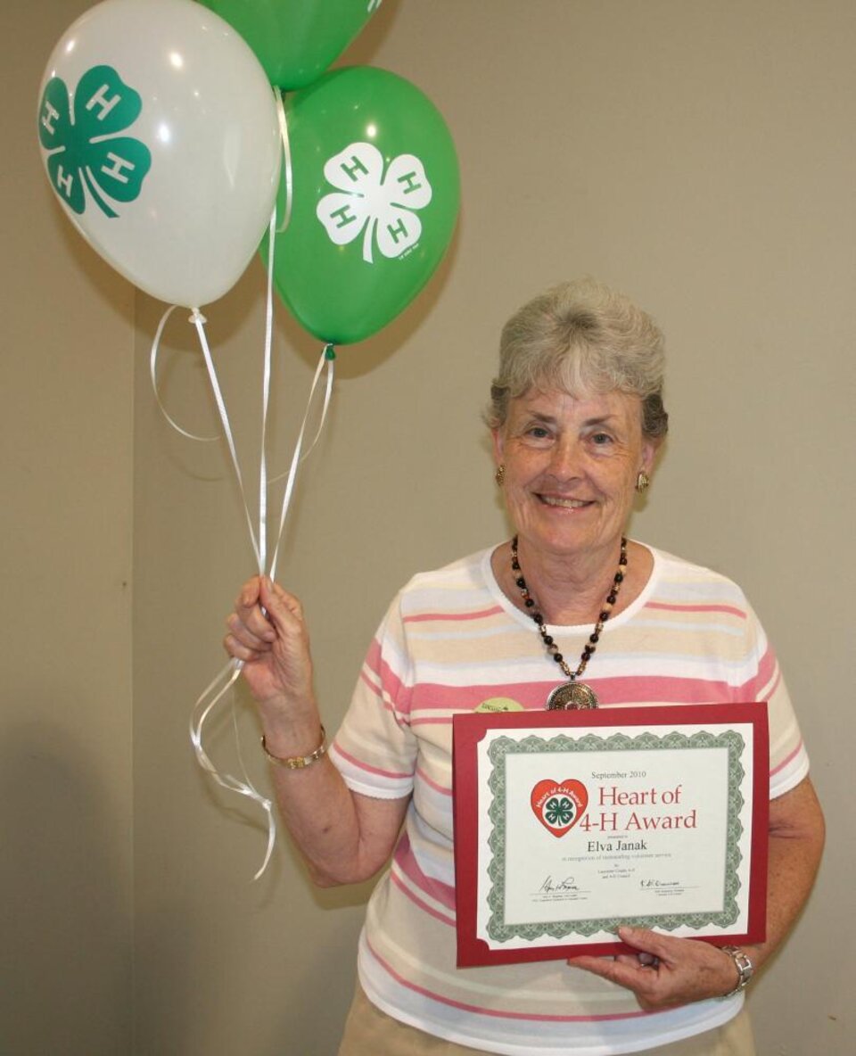 Elva Janak holding 4-H balloons and a certificate. 