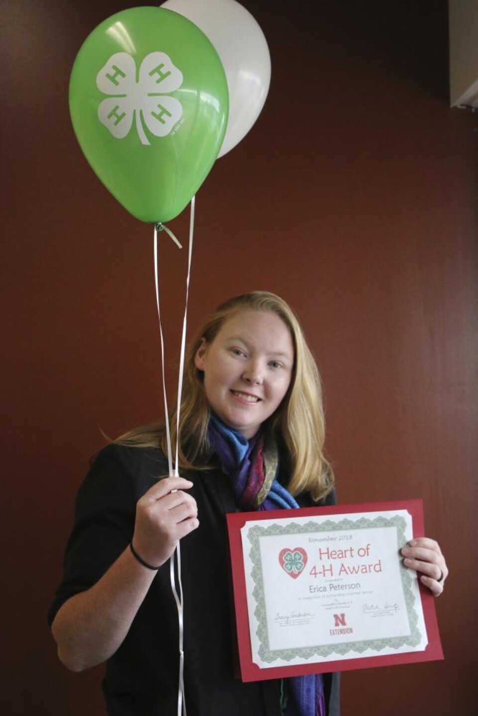 Erica Peterson holding 4-H balloons and a certificate. 