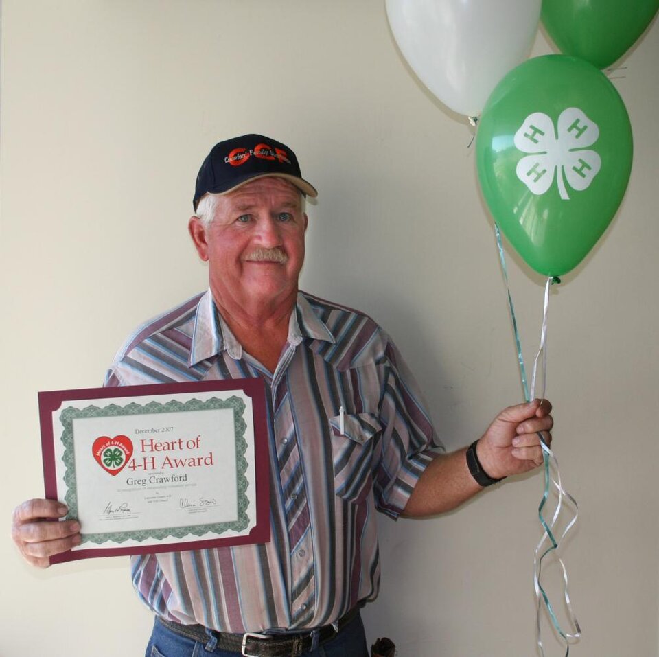 Greg Crawford holding balloons and a certificate 