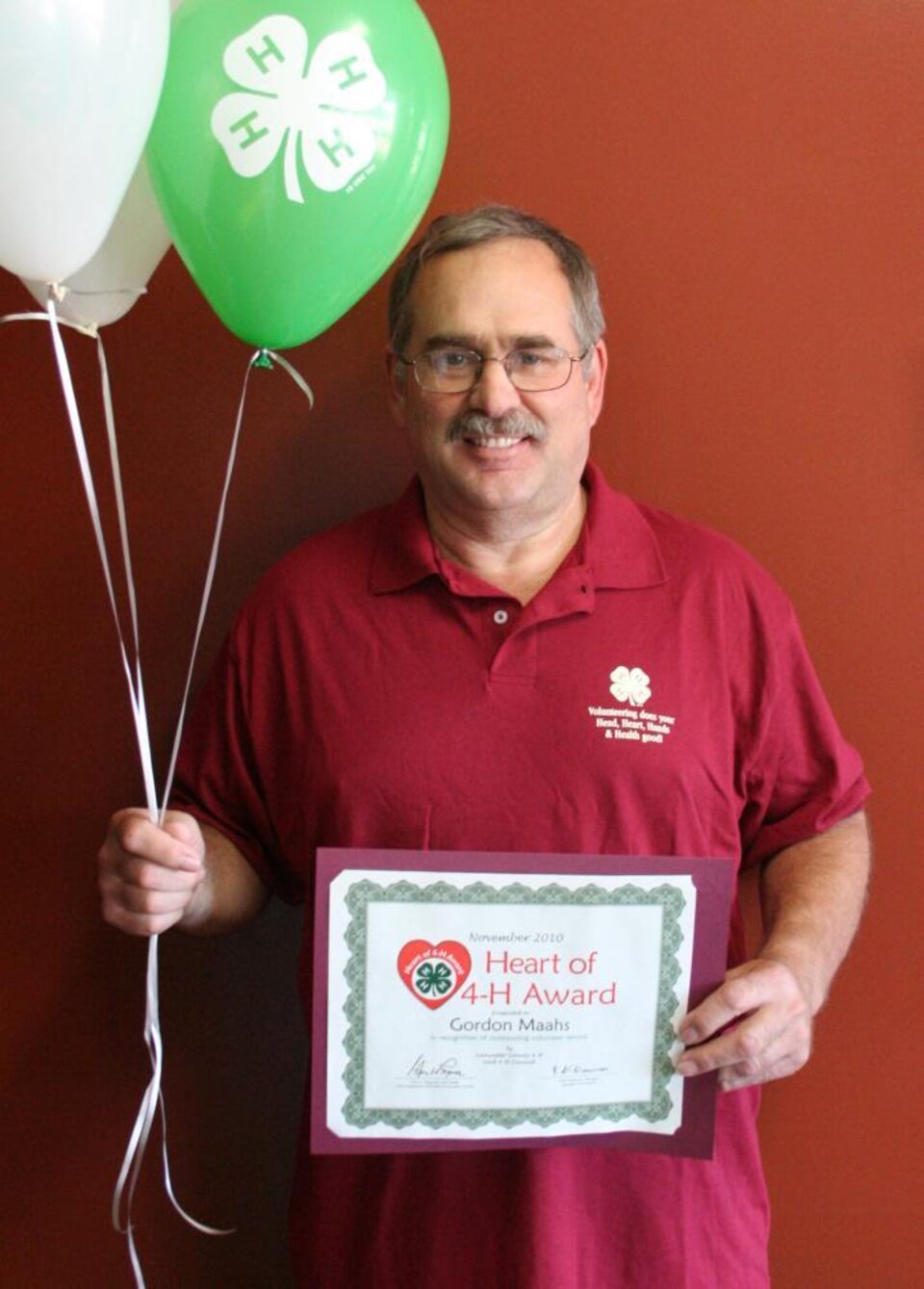 Gordon Maahs holding 4-H balloons and a certificate 