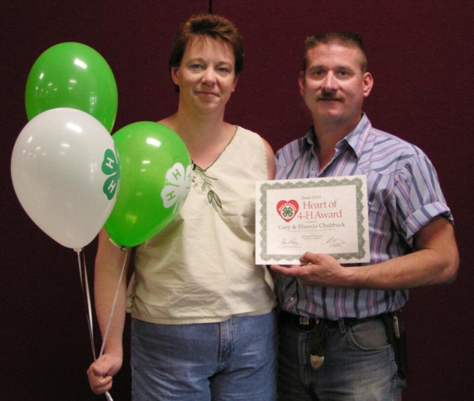 Gary Chubbuck holding a certificate and Rhonda Chubbuck holding balloons. 