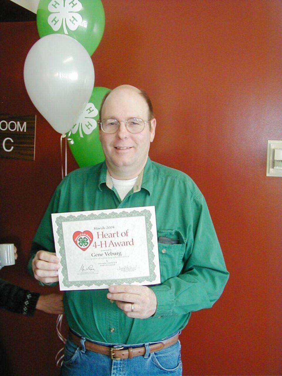 Gene Veburg holding balloons and a certificate 