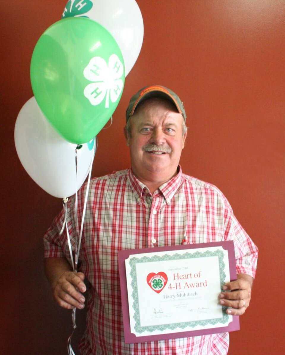 Harry Muhlbach holding balloons and a certificate 