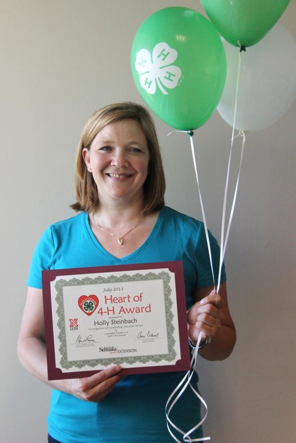 Holly Steinbach holding 4-H balloons and a certificate. 