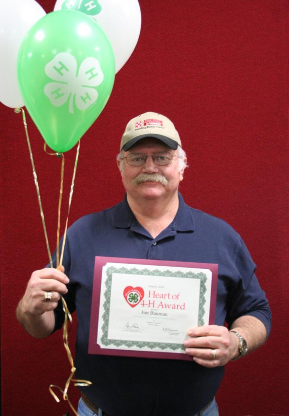 Jim Bauman holding balloons and a certificate 