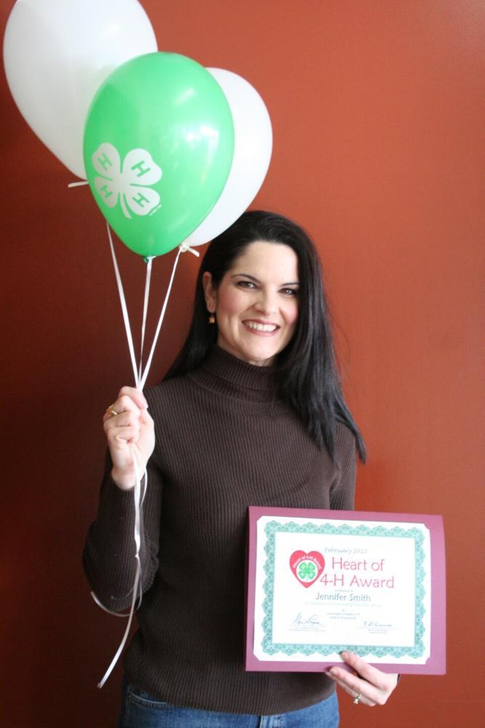 Jen Smith holding balloons and a certificate. 