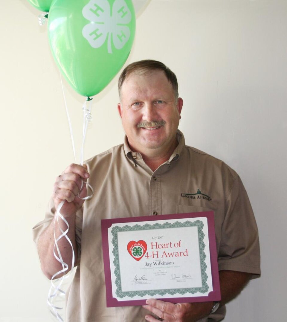 Jay Wilkinson holding balloons and a certificate 