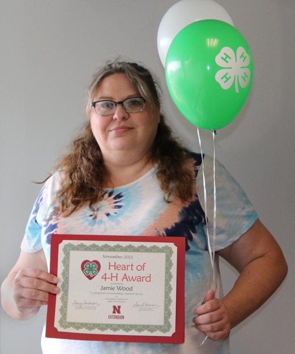 Jamie Wood holding 4-H balloons and a certificate. 